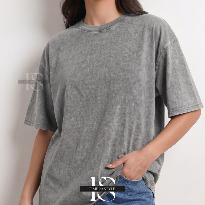 Pu&ograve; includere: Una maglietta grigia con lavaggio acido, a maniche corte e girocollo. La maglietta ha una vestibilit&agrave; leggermente oversize e un aspetto strutturato. L'indumento &egrave; abbinato a jeans blu. Il marchio "IEMERASTYLE" &egrave; visibile.