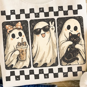 Op de afbeelding: Een crèmekleurig sweatshirt met een grafische print van drie geesten in rechthoekige kaders. De eerste geest draagt een strik en houdt een drankje vast, de tweede draagt een zonnebril en maakt een vredesteken, de derde houdt een zwarte kat vast.