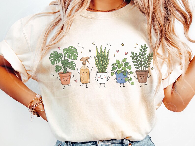 K&ouml;nnte beinhalten: Ein cremefarbenes T-Shirt mit einem Grafikdruck von f&uuml;nf anthropomorphen Charakteren: eine Monstera im Terrakottatopf, eine Spr&uuml;hflasche, eine Bogenhanfpflanze im wei&szlig;en Topf, eine Efeutute im blauen Topf und eine Gl&uuml;cksfeder im braunen Topf.