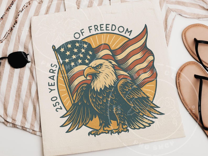 Może przedstawiać: Kremowa torba z ilustracją w stylu vintage amerykańskiego bielika i amerykańskiej flagi. Tekst brzmi "OF FREEDOM" i "250 YEARS". Orzeł jest w odcieniach niebieskiego, brązowego i kremowego.