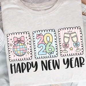 May include: A pale grey t-shirt featuring a colourful Happy New Year design. The design includes a disco ball, the numbers 2026, and champagne glasses. The text "HAPPY NEW YEAR" is printed in black.