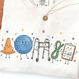 May include: A cream-colored t-shirt featuring a graphic print of five anthropomorphic objects: an orange traffic cone, a blue exercise ball, a silver walker, a green resistance band, and a brown clipboard with a checklist and bar graph.