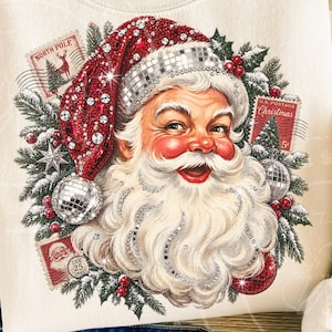 May include: A cream-colored sweatshirt featuring a graphic of Santa Claus wearing a red hat adorned with sparkling rhinestones and a disco ball texture. The design includes pine branches, red berries, and vintage-style postage stamps with text.