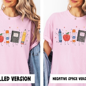 May include: Pale pink t-shirt with a cartoon design of school supplies: a crayon, apple, glue stick, notebook, and pencil, all with smiling faces. The design is decorated with stars. Text at the bottom reads "FILLED VERSION" and "NEGATIVE SPACE VERSION".