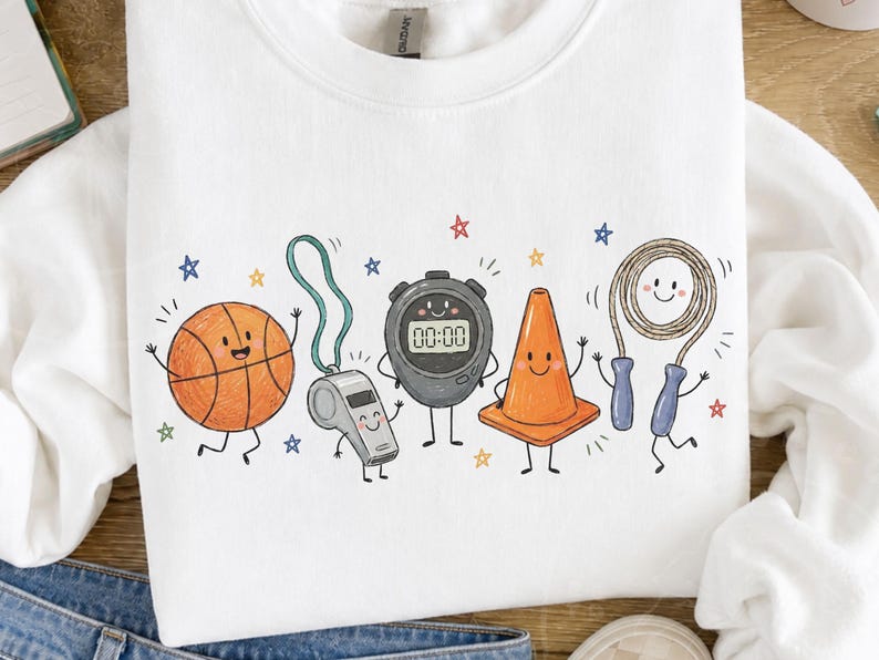 May include: A white crewneck sweatshirt featuring a graphic print of anthropomorphic sports equipment including an orange basketball, a silver whistle, a black stopwatch displaying 00:00, an orange traffic cone, and a jump rope with blue handles.