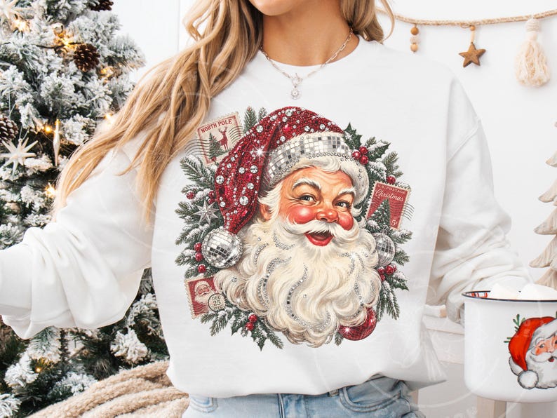 May include: A white long-sleeve sweatshirt featuring a graphic of Santa Claus wearing a red hat with a disco ball texture. The design includes green pine branches, red berries, and vintage-style postage stamps labeled North Pole and Christmas.