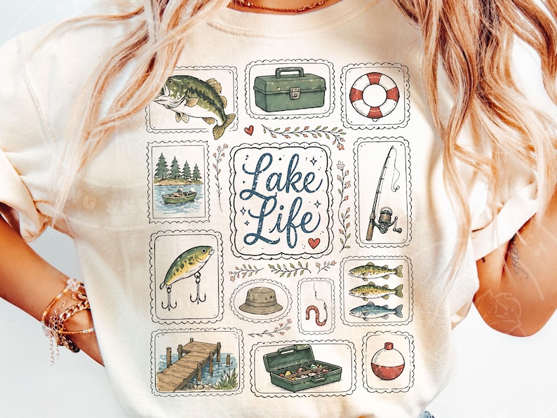 May include: Cream-colored t-shirt featuring a collection of fishing-themed illustrations. The design includes a fish, tackle box, life preserver, fishing rod, and the words "Lake Life". The illustrations are framed in decorative borders.