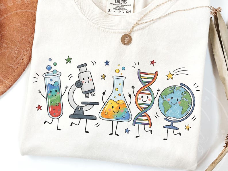 Puede incluir: Una camiseta de color crema con un estampado gr&aacute;fico colorido de objetos cient&iacute;ficos antropom&oacute;rficos, incluyendo un tubo de ensayo, un microscopio, un matraz Erlenmeyer, una cadena de ADN y un globo terr&aacute;queo, todos con caras sonrientes y extremidades negras.