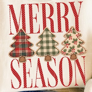 Può includere: Una felpa color crema con il testo rosso MERRY SEASON in un motivo a pois bianchi. Tra le parole ci sono tre alberi di Natale applicati: uno con un motivo scozzese rosso e verde, uno con un motivo vichy verde e bianco e uno con stampa di agrifoglio.