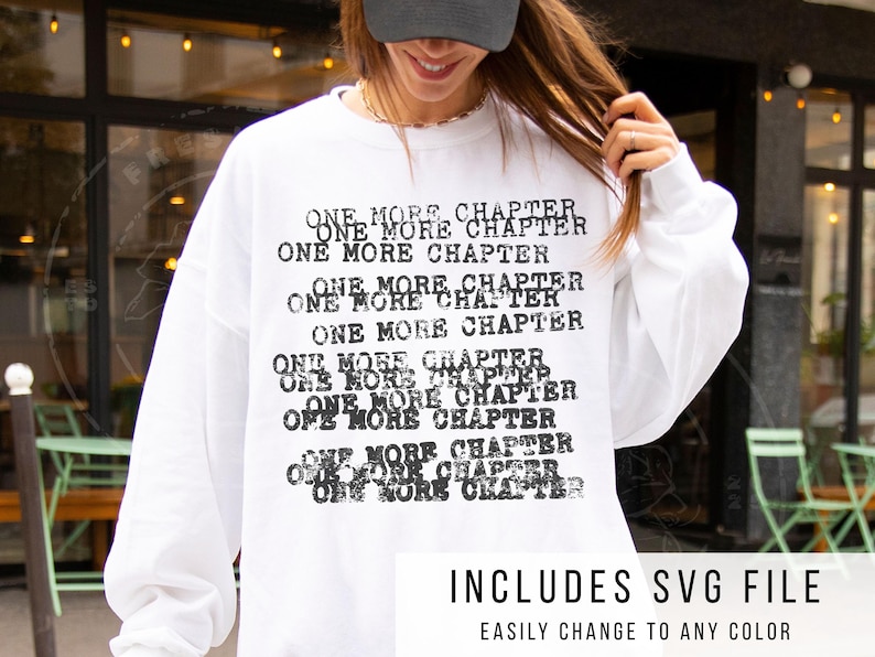 K&ouml;nnte beinhalten: Wei&szlig;es Sweatshirt mit dem Text "ONE MORE CHAPTER" in verblichener schwarzer Schrift. Der untere Teil des Bildes enth&auml;lt den Text "INCLUDES SVG FILE" und "EASILY CHANGE TO ANY COLOR".