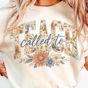 May include: Cream-colored sweatshirt with the words "TEACH called to TEACH" in a floral design. The word "TEACH" is in large block letters filled with a floral pattern. A floral arrangement is at the bottom.