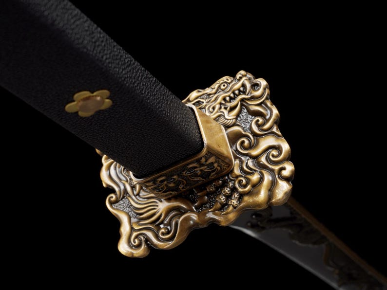 May include: Close-up of a katana sword hilt. The black handle is adorned with a gold flower emblem. The guard features an ornate, gold dragon design. The blade is visible, with a dark finish.