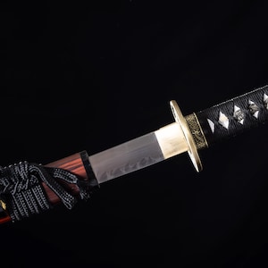 May include: A close-up of a Japanese katana sword. The blade is silver, with a gold tsuba and a black handle wrapped in a diamond pattern. The scabbard is a dark red color, and the background is black.