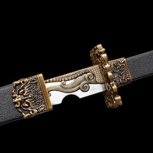 May include: Close-up of a decorative sword with a black handle and a silver blade. The hilt and guard are ornate, featuring gold-colored lion and dragon designs. A gold flower decorates the handle.
