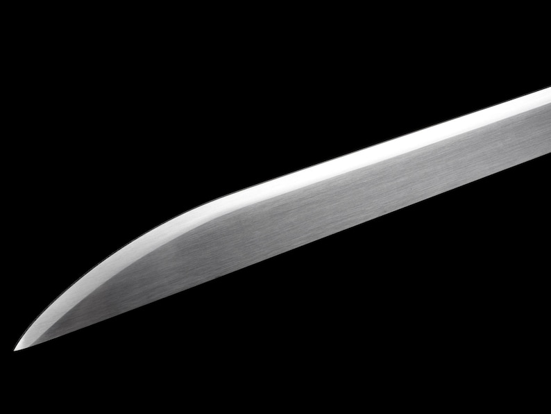 May include: Close-up of a polished, silver-colored sword blade against a black background. The blade has a curved edge and a flat top, reflecting light. The image highlights the sharpness and metallic texture of the weapon.