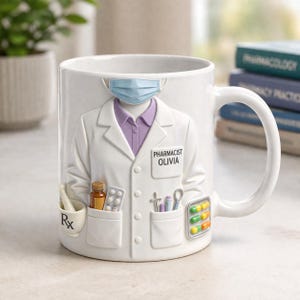 May include: White ceramic mug with a pharmacist design. The mug features a relief of a lab coat, a face mask, and pockets with pills, a mortar and pestle, and medical tools. The name "OLIVIA" is printed on the lab coat.
