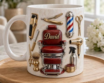 Puede incluir: Una taza de cerámica blanca con un diseño en relieve de una silla de barbero roja con el nombre David en letras doradas. Alrededor de la silla hay herramientas de barbero doradas: cortapelos, navaja, tijeras, secador, pulverizador, brocha de afeitar y un poste de barbero rojo, blanco y azul.