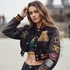 Può includere: Una giacca varsity nera con maniche in pelle, caratterizzata da polsini e colletto a coste a righe gialle e nere. La giacca presenta una grande lettera A gialla con il numero 1591, varie toppe ricamate sulla manica e del testo dorato.