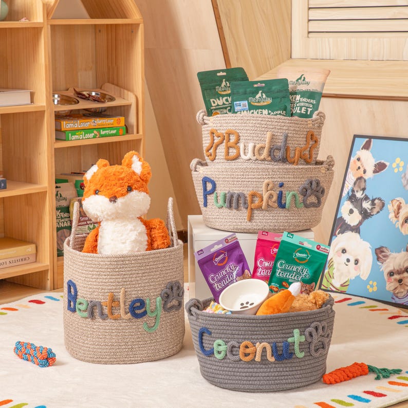 May include: Several woven rope baskets for pets, labelled with names such as "Bentley", "Buddus", "Pumpkin", and "Coconut". The baskets contain pet supplies and toys, including a plush fox. The lettering on the baskets is in various colours.