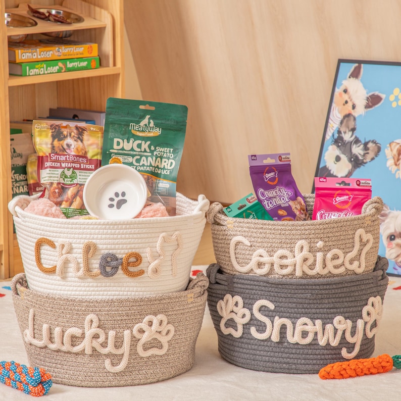 May include: Four woven rope pet baskets, stacked. The top basket is white with "Chloe" and a cat silhouette. The next basket is tan with "Lucky" and a paw print. The other two baskets are tan and grey with pet names.