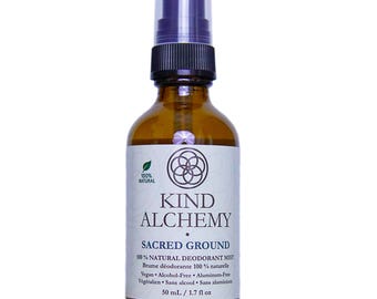 Könnte beinhalten: Eine braune Glasflasche mit Kind Alchemy Sacred Ground Deodorant-Nebel. Die Flasche hat einen schwarzen Sprühkopf und ein weißes Etikett mit Text und einem Logo. Das Etikett gibt an, dass das Produkt zu 100 % natürlich, vegan und alkoholfrei ist. Die Flasche enthält 50 ml.