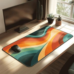 Puede incluir: Alfombrilla de ratón rectangular con un diseño de ondas retro en tonos naranja, turquesa y amarillo. Un ratón de ordenador negro está en el lado izquierdo de la alfombrilla. La alfombrilla está sobre un escritorio de madera.