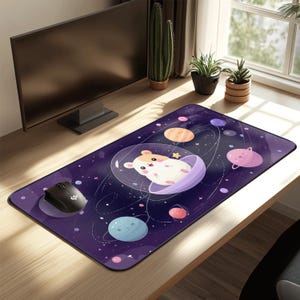 May include: A rectangular purple mouse pad featuring a cartoon hamster in a space-themed design. The pad has planets, stars, and a hamster in a spaceship. A black mouse sits on the pad.