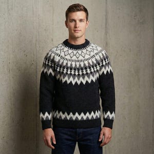 Puede incluir: Un suéter gris oscuro con un patrón geométrico en blanco, gris claro y negro alrededor del canesú. El suéter tiene cuello redondo y mangas largas. El modelo lleva vaqueros azules.