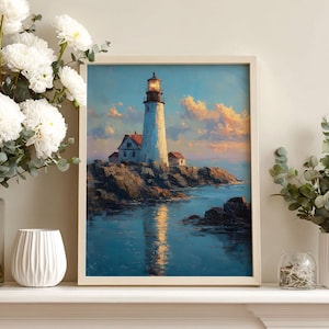 Op de afbeelding: Ingelijste kunstprint van een vuurtoren op een rotsachtige kust bij zonsondergang. De vuurtoren is wit met een rood dak, tegen een blauwe lucht met oranje en gele wolken. Het kunstwerk wordt getoond op een witte schoorsteenmantel.