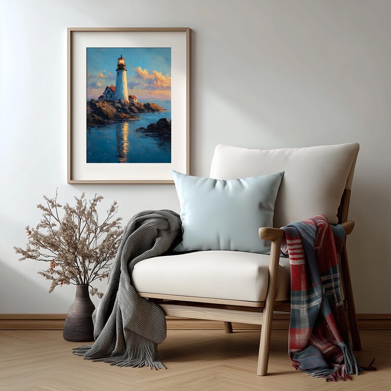 May include: A framed painting of a lighthouse on a rocky coast, with a lit beacon. The artwork is displayed above a white armchair with a light blue pillow, a gray blanket, and a plaid throw. A vase with dried branches is on the left.