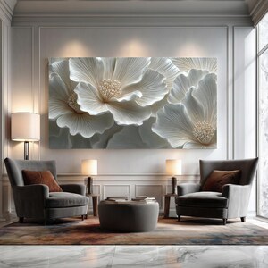 May include: A large, rectangular wall art piece featuring a detailed, textured relief of white flowers. The artwork is the focal point of a room with two gray armchairs, lamps, and a round ottoman. The room has a modern, elegant aesthetic.