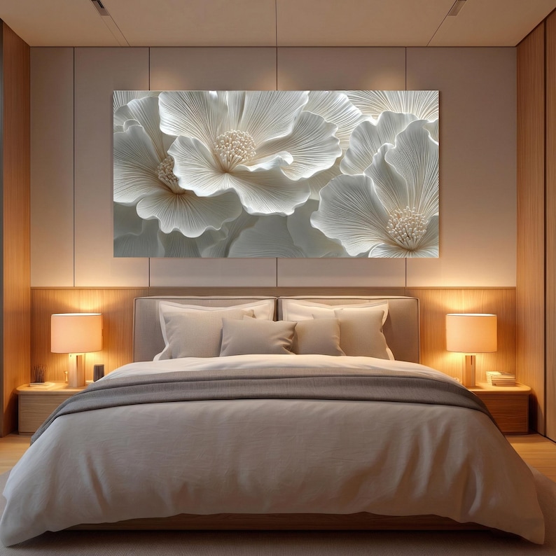 May include: A large, white floral wall art piece hangs above a bed. The artwork features a close-up of several large, textured flowers with detailed petals and a central, textured core. The bedroom has neutral tones and warm lighting.