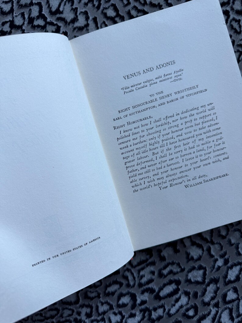 May include: Open book with text from "Venus and Adonis" by William Shakespeare. The text is printed in black ink on off-white paper. The phrase "Printed in the United States of America" is at the bottom.