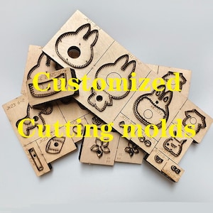 Puede incluir: Moldes de corte de madera en varias formas, incluyendo caras de conejos, flores y prendas de vestir. Los moldes están dispuestos en un patrón en capas, con el texto "Customized Cutting molds" en amarillo.