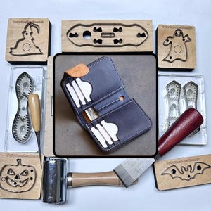 May include: A handmade leather wallet in navy blue with white stitching, open to display card slots and a cash pocket. Surrounding the wallet are various leatherworking tools and wooden stamps with Halloween-themed designs.