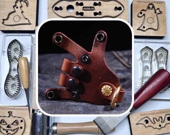 May include: A brown leather holster with black hardware and a gold-colored accent ring. Surrounding the holster are various wooden craft tools and stamps, including a mallet, a blade, and Halloween-themed designs.
