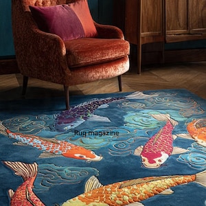 Pode incluir: Um tapete azul com um desenho bordado de peixes koi nadando em um lago. Os peixes são em tons de laranja, vermelho, amarelo e roxo. O tapete está em uma sala com uma poltrona de veludo e um armário de madeira.