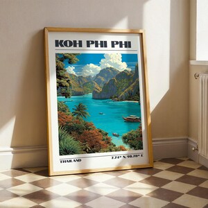 May include: A framed vertical travel poster featuring a vibrant illustration of Koh Phi Phi, Thailand. The artwork depicts turquoise waters, limestone cliffs, lush tropical foliage, and traditional long-tail boats. Text reads Koh Phi Phi, Thailand, 7.74° N, 98.78° E.