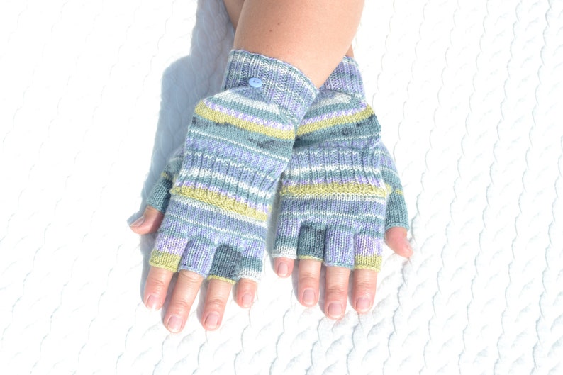 Hand knitted green striped convertible half finger gloves with mitten flaps on model's hands