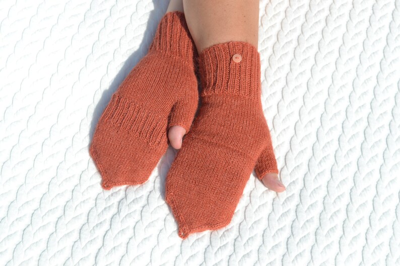 Hand knitted terracotta / copper alpaca convertible gloves with mitten flap on model's hands