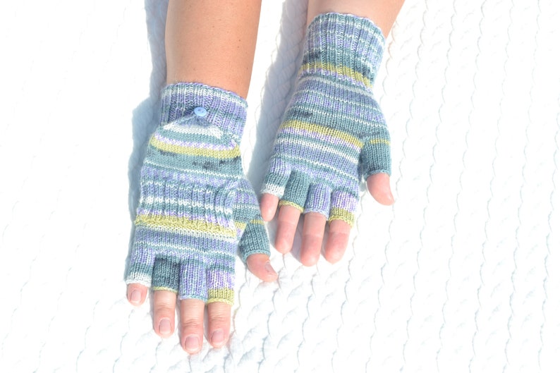 Hand knitted green striped convertible half finger gloves with mitten flaps on model's hands