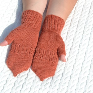 Hand knitted terracotta / copper alpaca convertible gloves with mitten flap on model's hands