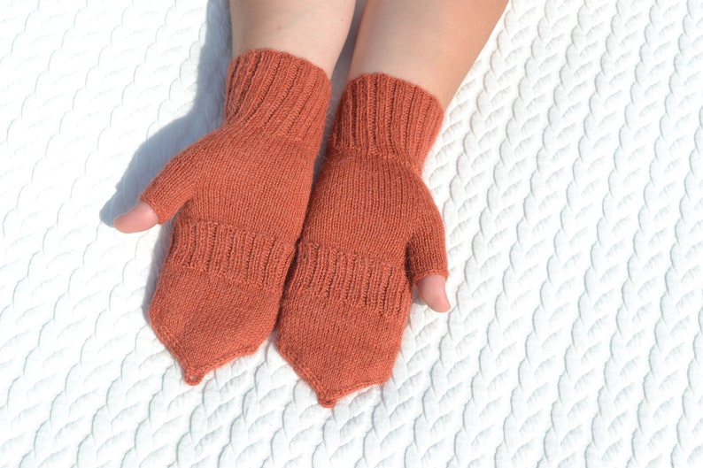 Hand knitted terracotta / copper alpaca convertible gloves with mitten flap on model's hands