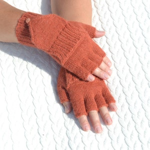 Hand knitted terracotta / copper alpaca convertible gloves with mitten flap on model's hands