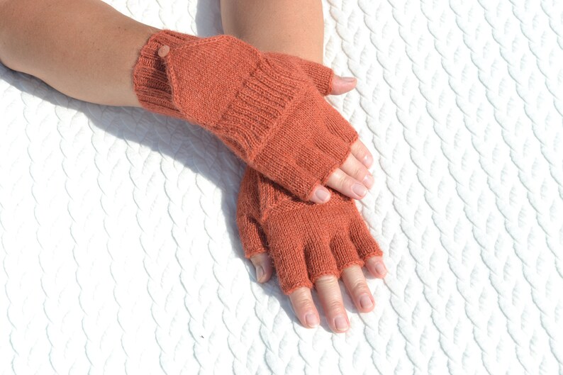 Hand knitted terracotta / copper alpaca convertible gloves with mitten flap on model's hands