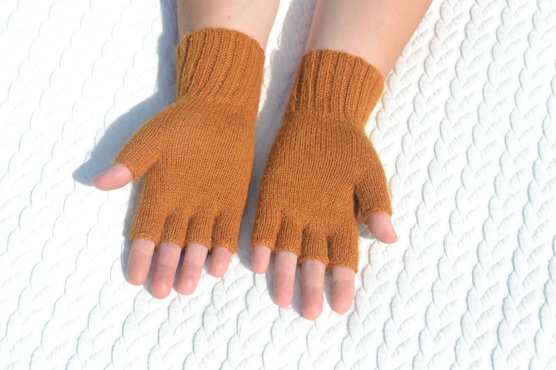 Handmade ocher alpaca half finger gloves on model's hands