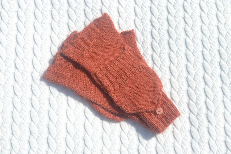 Hand knitted terracotta / copper alpaca convertible gloves with mitten flap on model's hands