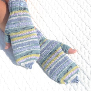 Hand knitted green striped convertible half finger gloves with mitten flaps on model's hands