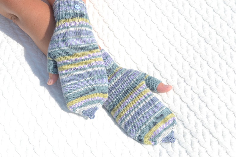 Hand knitted green striped convertible half finger gloves with mitten flaps on model's hands