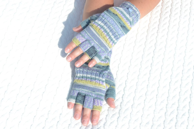 Hand knitted green striped convertible half finger gloves with mitten flaps on model's hands
